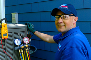 Betlem HVAV Technician Outside A Home Kneeling Next To An Air Conditioner with Gauges Taached To It